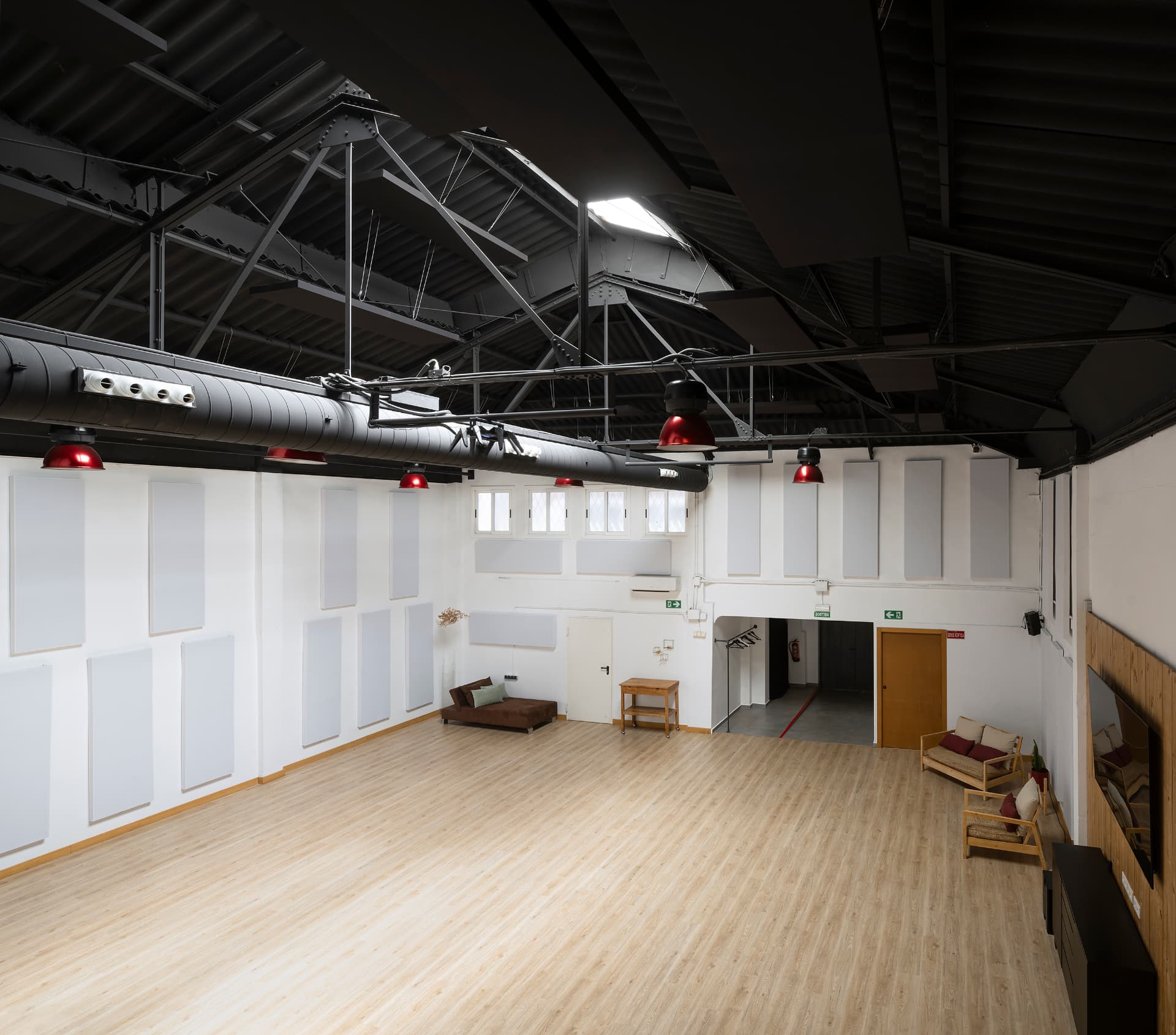 Sala principal diáfana vista desde el altillo, con paneles acústicos y suelo de madera