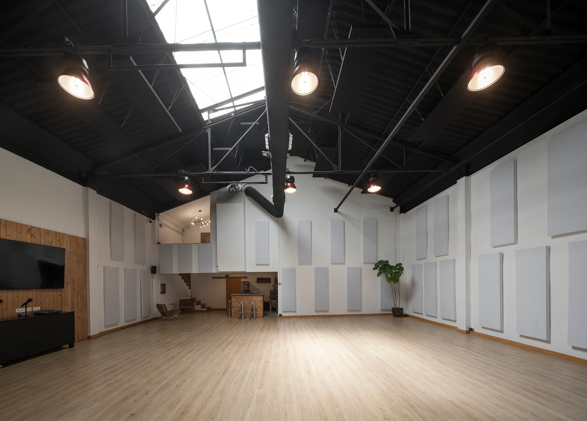 Fotografía actual de la sala principal vacía de M&F Espai+ con paredes blancas y suelo de madera